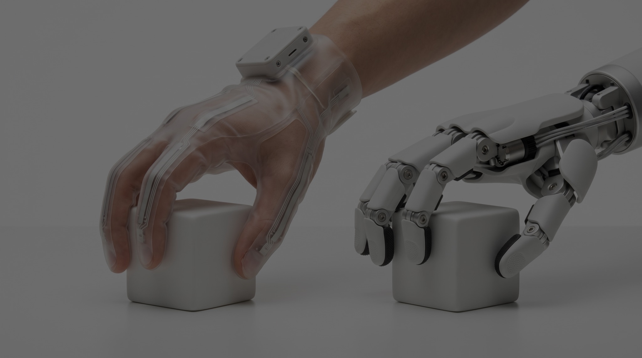 A human hand in a tactile glove and a robot hand each grasping a white cube